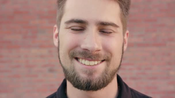 Feliz hombre sonriente con barba contra una pared de ladrillo — Vídeos de Stock