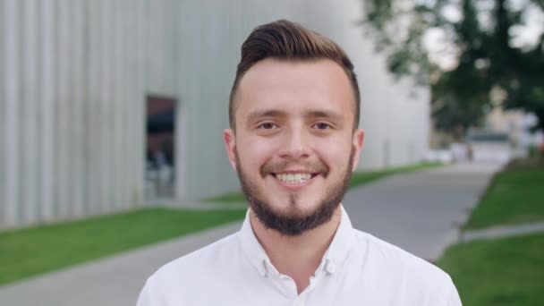 Νεαρός άνδρας, φορώντας ένα άσπρο πουκάμισο χαμογελώντας στην πόλη — Αρχείο Βίντεο