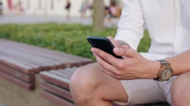 Oturma ve şehirde bir telefonu kullanarak genç adam