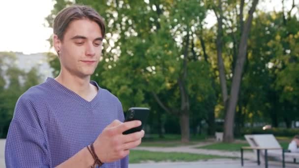 Jonge Man lopen en met behulp van een telefoon in de stad — Stockvideo