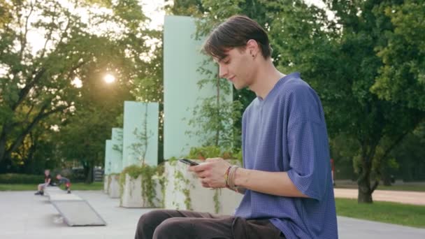 Junger Mann sitzt und telefoniert in der Stadt — Stockvideo