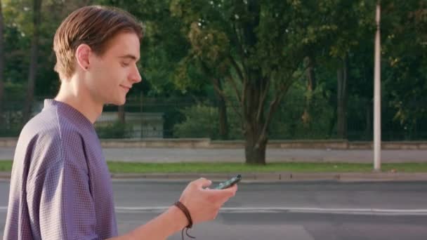 Junger Mann zu Fuß und mit dem Handy in der Stadt — Stockvideo