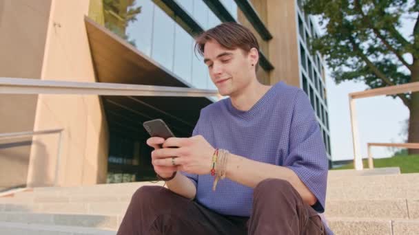 Jonge Man zitten en met behulp van een telefoon in de stad — Stockvideo