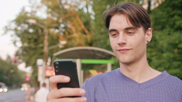 Νεαρός άνδρας χρησιμοποιώντας ένα τηλέφωνο στην πόλη — Αρχείο Βίντεο