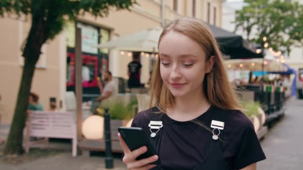 Joven pelirroja usando un teléfono en la ciudad — Vídeos de Stock