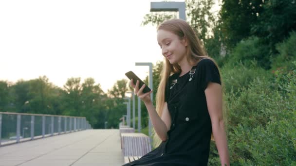 Ung rödhårig dam med en telefon i stan — Stockvideo