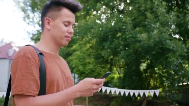 Mladý muž, chůzi a používání telefonu ve městě — Stock video