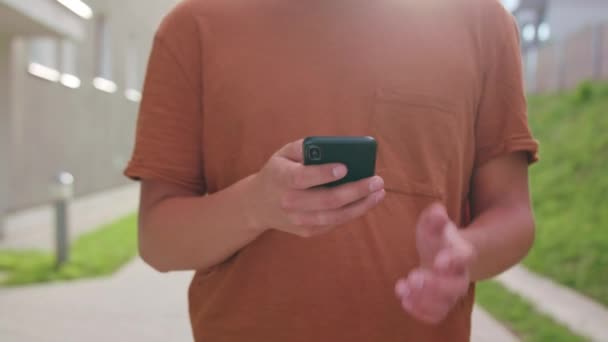 Молодий чоловік ходить і використовує телефон у місті — стокове відео