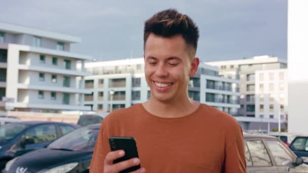 Homem jovem andando e usando um telefone na cidade — Vídeo de Stock