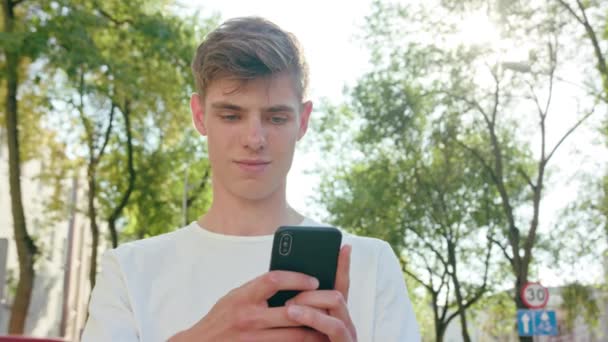 Νεαρός άνδρας χρησιμοποιώντας ένα τηλέφωνο στην πόλη — Αρχείο Βίντεο
