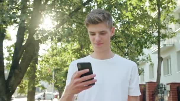 Homem jovem andando e usando um telefone na cidade — Vídeo de Stock