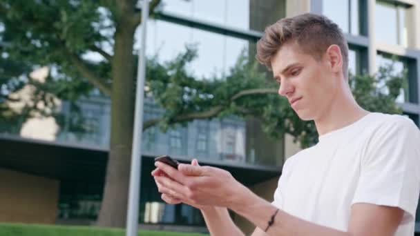 Joven caminando y usando un teléfono en la ciudad — Vídeos de Stock