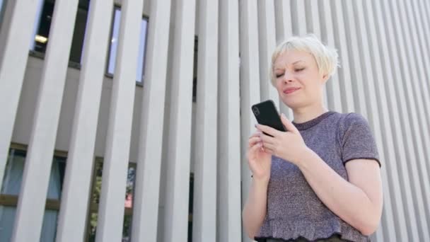 街で携帯電話を使用して若いブロンドの女性 — ストック動画