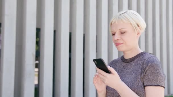Молодая блондинка, использующая телефон в городе — стоковое видео