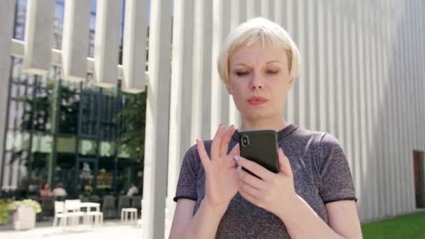 Jeune femme blonde utilisant un téléphone en ville — Video