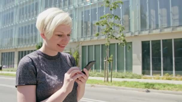 Giovane signora bionda utilizzando un telefono in città — Video Stock