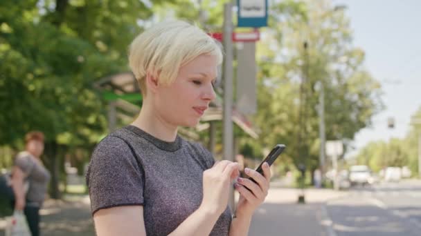 Молода блондинка використовує телефон у місті — стокове відео