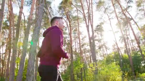 Молодий чоловік біжить у лісі — стокове відео