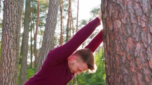 Jeune homme s'étirant dans la forêt — Video