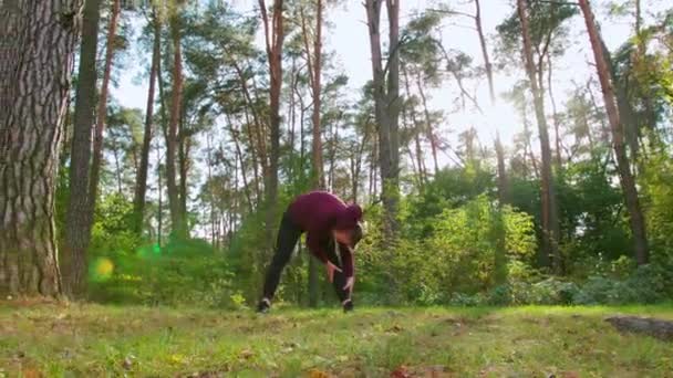 Ung man stretching i skogen — Stockvideo