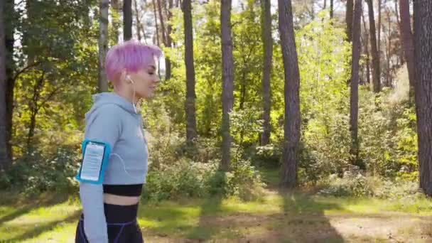 Девушка с розовыми волосами бегает в лесу — стоковое видео