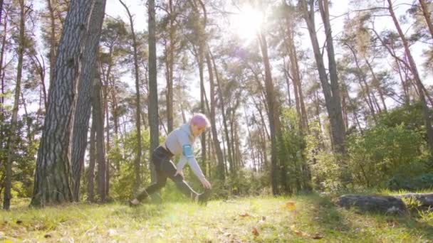 Jeune femme aux cheveux roses s'étendant dans la forêt — Video