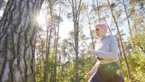 Jovencita con el pelo rosado estirándose en el bosque — Vídeo de stock