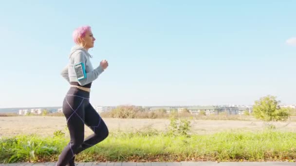 Девушка с розовыми волосами бегает трусцой в пригороде — стоковое видео