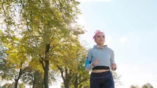 Junge Frau mit rosa Haaren joggt im Wald — Stockvideo