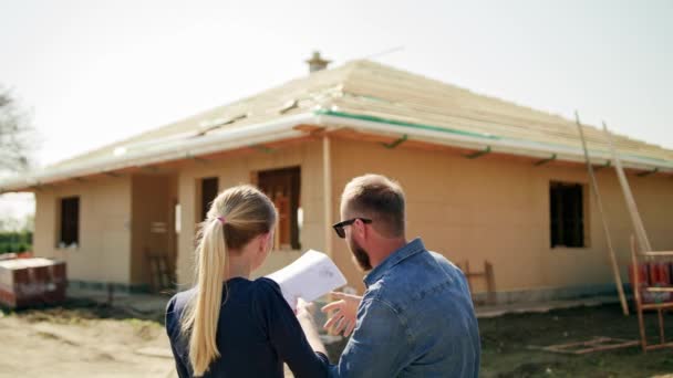 Dos jóvenes discutiendo la construcción de una casa — Vídeo de stock