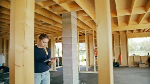 Egy Fiatal Hölgy Segítségével Egy Tablettát Egy Házat Építés Alatt — Stock videók