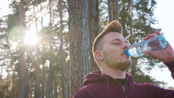 Ung Man dricksvatten i skogen — Stockfoto