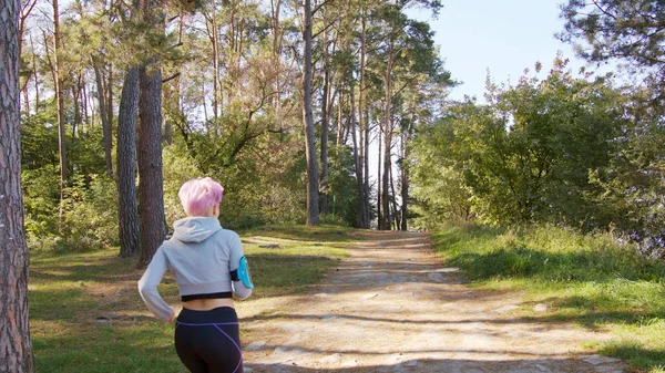 Joven dama con el pelo rosa corriendo en el bosque — Foto de Stock