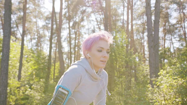 Joven dama con el pelo rosa corriendo en el bosque — Foto de Stock