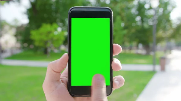 A Hand Holding a Phone with a Green Screen