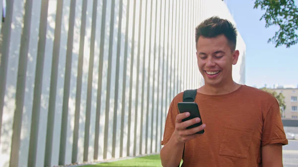 Homem jovem andando e usando um telefone na cidade — Fotografia de Stock