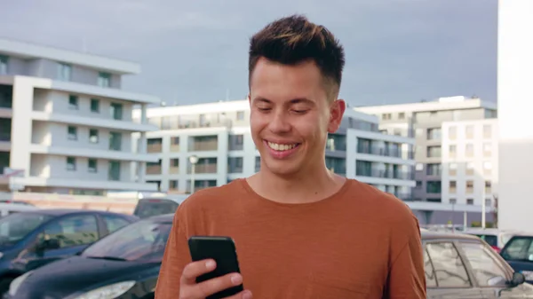 Homem jovem andando e usando um telefone na cidade — Fotografia de Stock