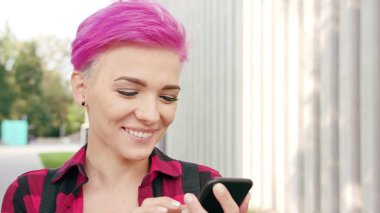 Kasabada bir telefonu kullanarak pembe kısa saçlı kadın