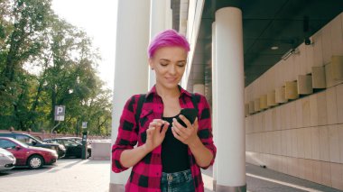 Kasabada bir telefonu kullanarak pembe kısa saçlı kadın