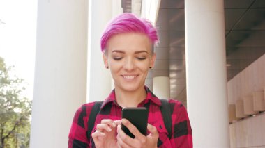 Kasabada bir telefonu kullanarak pembe kısa saçlı kadın