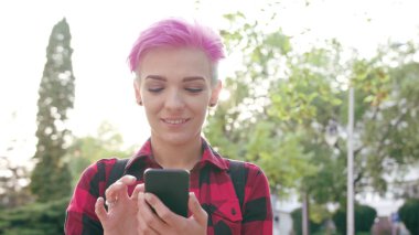 Kasabada bir telefonu kullanarak pembe kısa saçlı kadın