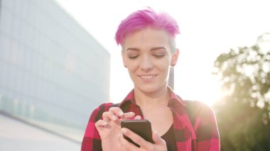 Kasabada bir telefonu kullanarak pembe kısa saçlı kadın