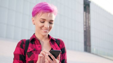 Kasabada bir telefonu kullanarak pembe kısa saçlı kadın