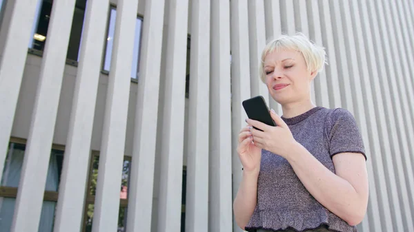 Молодая блондинка, использующая телефон в городе — стоковое фото