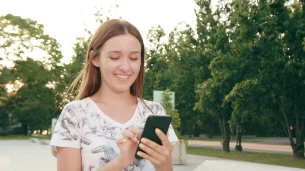 Jovencita usando un teléfono en la ciudad mientras camina — Foto de Stock