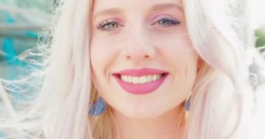 Sarışın bayan dışarıda gülümsüyor.