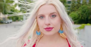 Sarışın bayan dışarıda gülümsüyor.