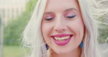 Sarışın bayan dışarıda gülümsüyor.