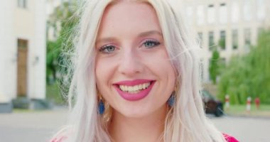 Sarışın bayan dışarıda gülümsüyor.