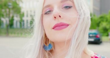 Sarışın bayan dışarıda gülümsüyor.